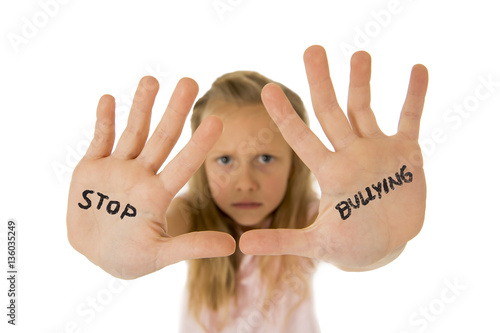 sweet and scared little schoolgirl showing the text stop bullying written in her hands photo