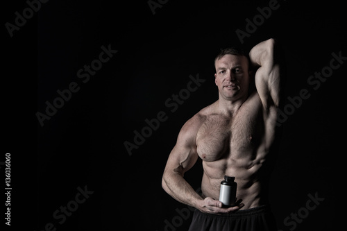 handsome sexy athlete man with muscular body holds plastic jar or container