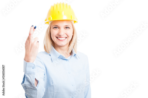 Female engineer wearing helmet showing fingers crossed