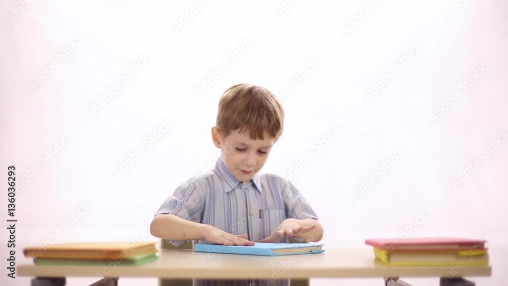 Funny four-year boy sitting at school desk, he's trying to read the book, turns it in different directions
Funny four-year boy sitting at school desk, he's trying to read the book, turns it in different directions