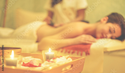 Young woman having hot stone therapy massage in spa resort hotel