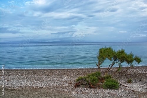 View of pebbly beach on cloudy day on western coast of Rhodes Island  Aegean Sea and Turkey coast in the background  Ialyssos  Greece