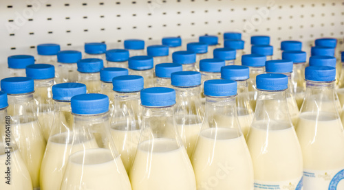 many plastic bottles with milk inside with bright blue covers against metal background in the shop