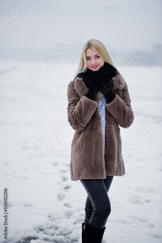 Portrait of young elegance blonde girl in a fur coat background