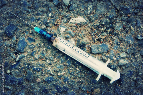 Used syringe with blood on the asphalt