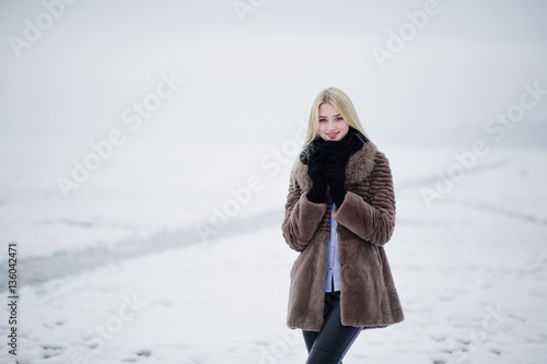 Portrait of young elegance blonde girl in a fur coat background