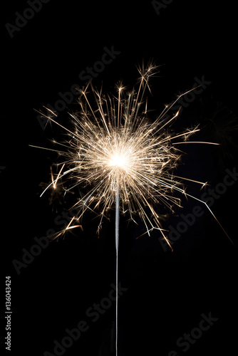 A burning sparkler on a black background