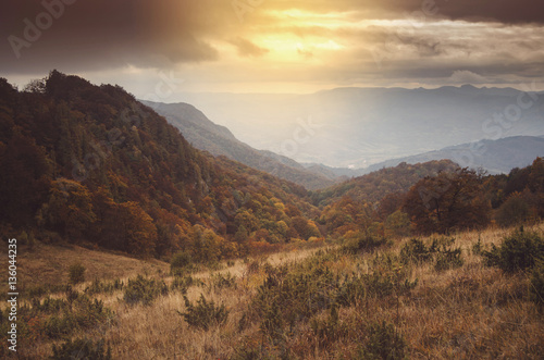 Sunset light in mountain landscape. Hills and forests seen from above in autumn scenery