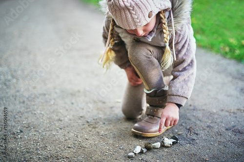 Cuadro en lienzo Little girl touches stones on a road