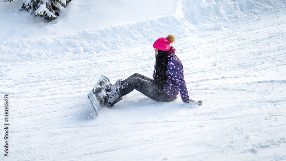 girl snowboarder fell and sitting on the snow
