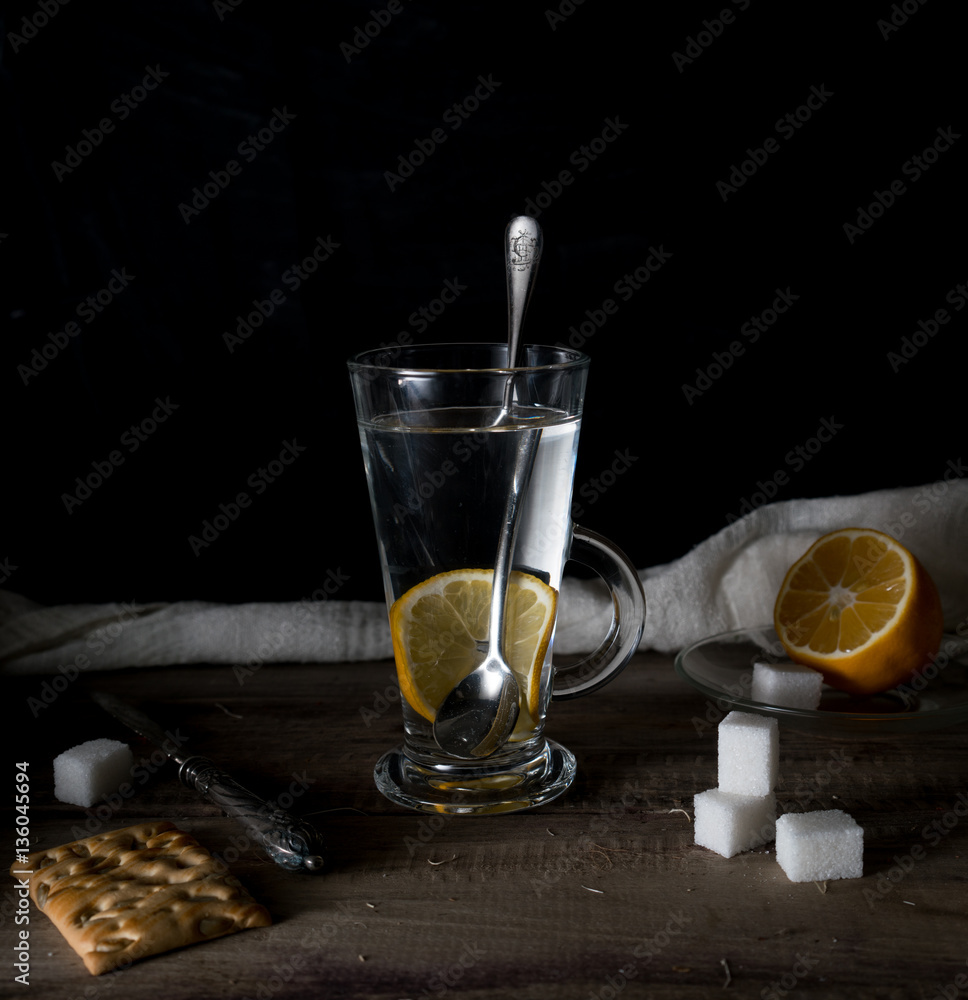 rustic still life. Tea with lemon in a large circle on the wooden table. black background
