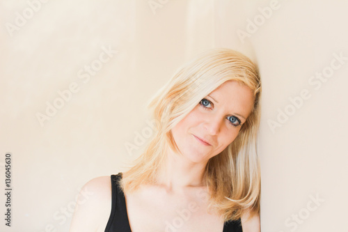 Young woman portrait with head leaning against the wall photo from front