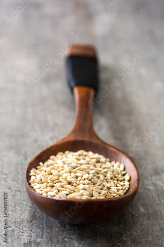 Sesame seeds on wooden spoon on wooden background
