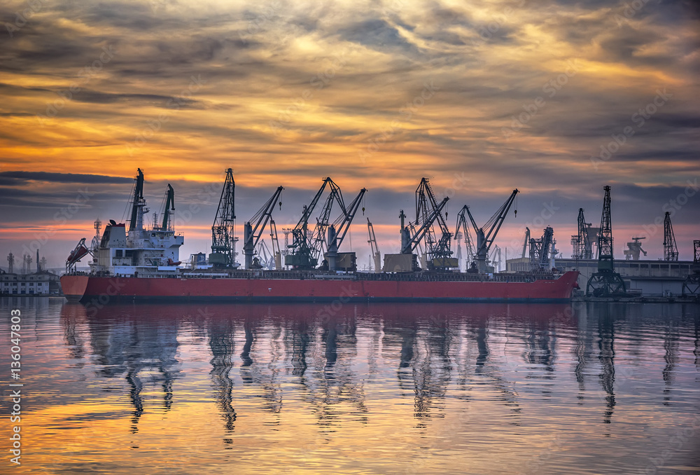 Ship and cranes in port at sunset. Cargo ship terminal at twilight scene. Ship and cranes in port at sunset. Cargo ship terminal at twilight scene.