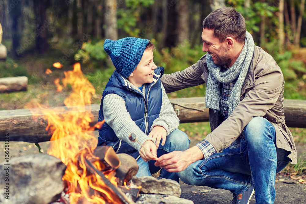 father and son roasting marshmallow over campfire father and son roasting marshmallow over campfire