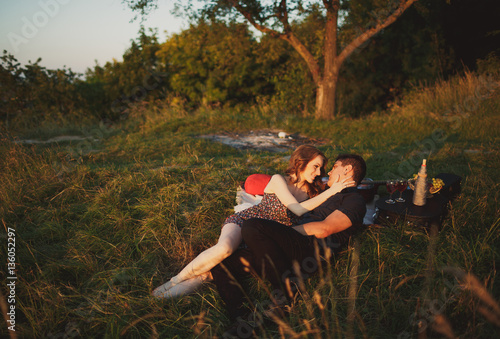 The charming couple in love sits on the grass
