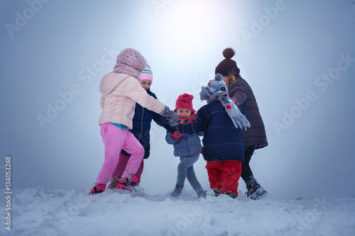Five children are having fun in the snow.