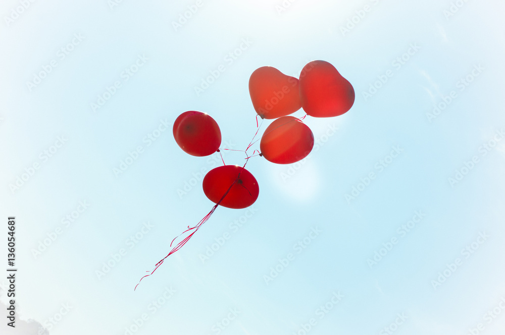 Inflatable helium balloons in the form of red hearts on a blue summer sky. Bunch of balloons rising into the sky. Love.
