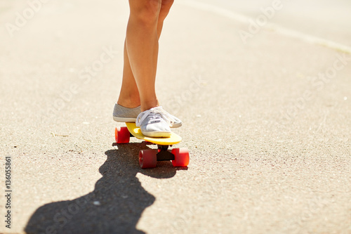 legs of young woman riding skateboard on road