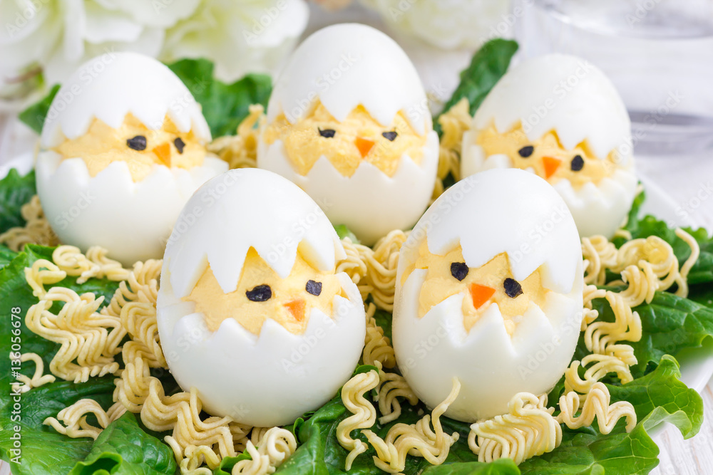 Little chicken in nest, deviled eggs served with salad and dry ramen on white plate, horizontal Little chicken in nest, deviled eggs served with salad and dry ramen on white plate, horizontal