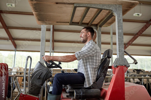 man or farmer driving tractor at farm