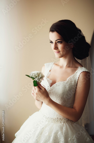 beautiful bride holding gentle boutoniere of the groom photo