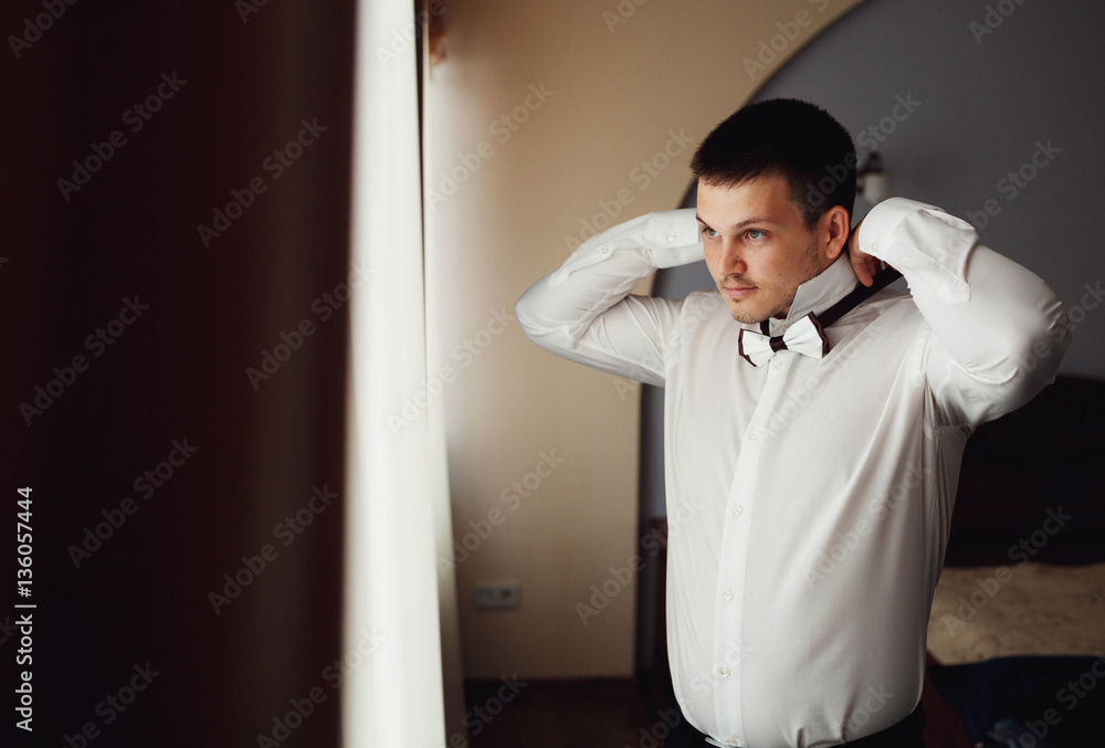 handsome groom getting dressed and preparing for the wedding handsome groom getting dressed and preparing for the wedding