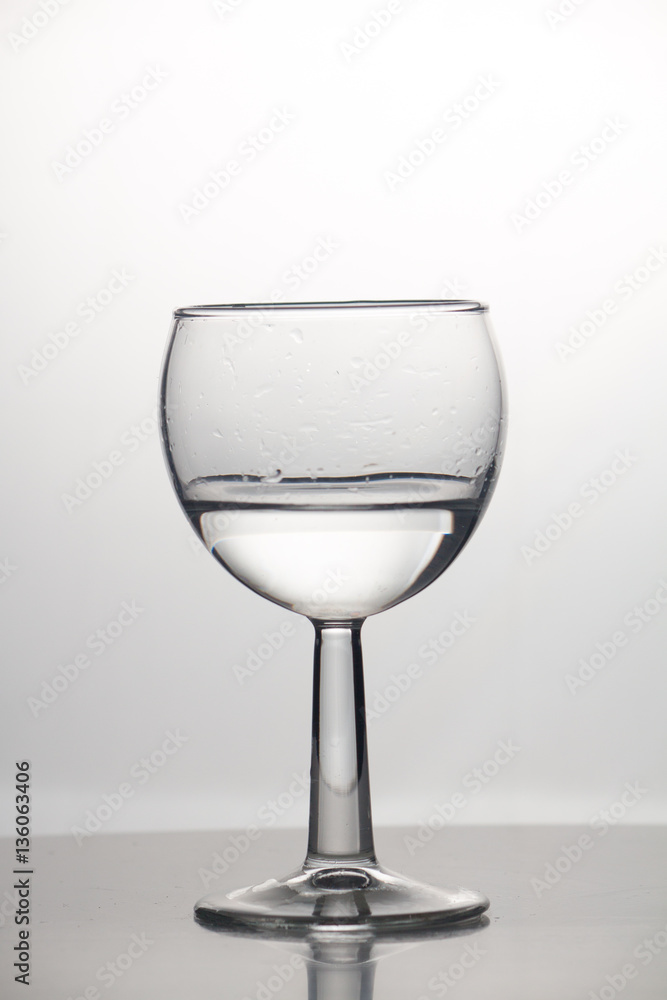 Obraz premium Transparent glass cup with a pouring bubbling cold fresh water with bubbles and drops