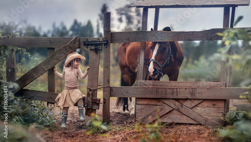 Foto Cute girl feeding her horse in paddock