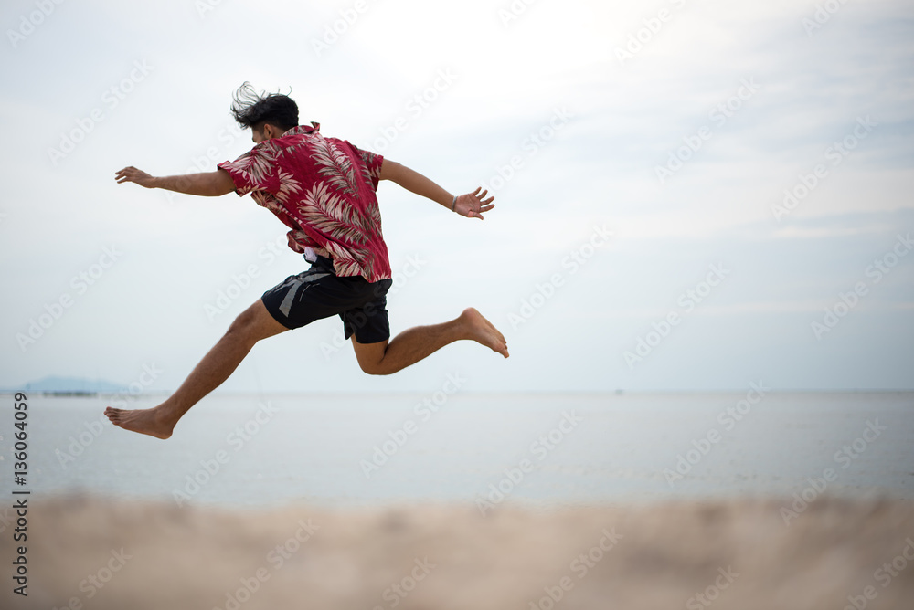 Athletic young man enjoying the summer, jumping in a tropical beach