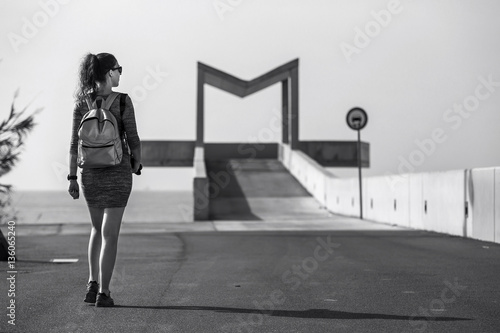 Young and attractive woman is walking away along the path in urb