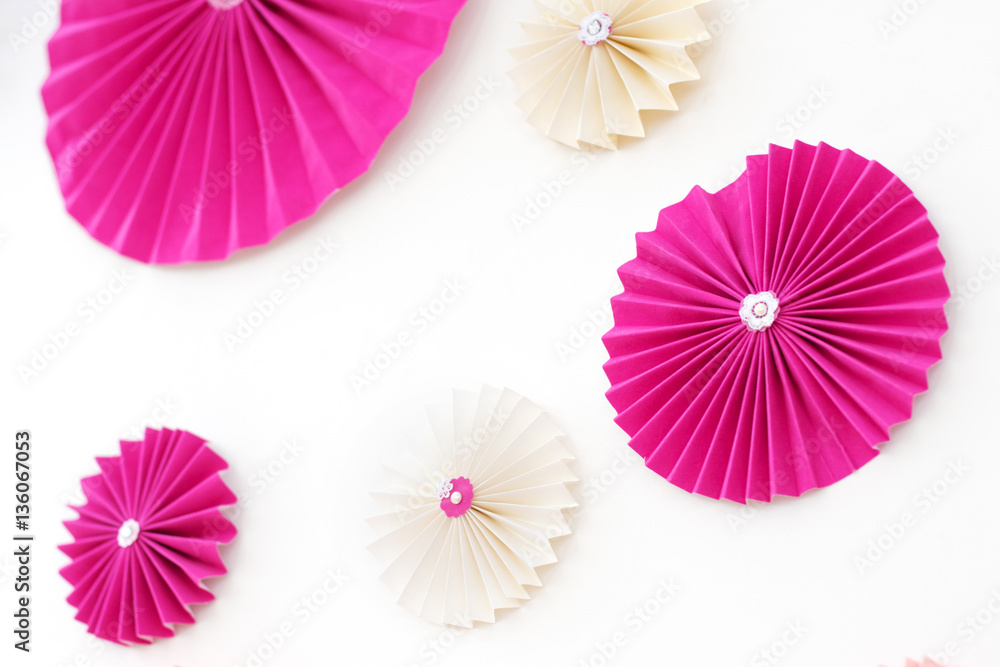 Decor. Pink paper flowers on a white wall.