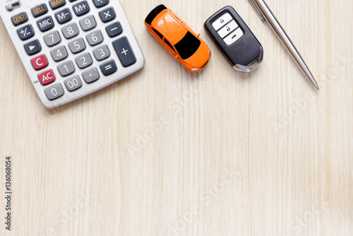 Top view of car key, car toy, pen and calculator on wooden desk