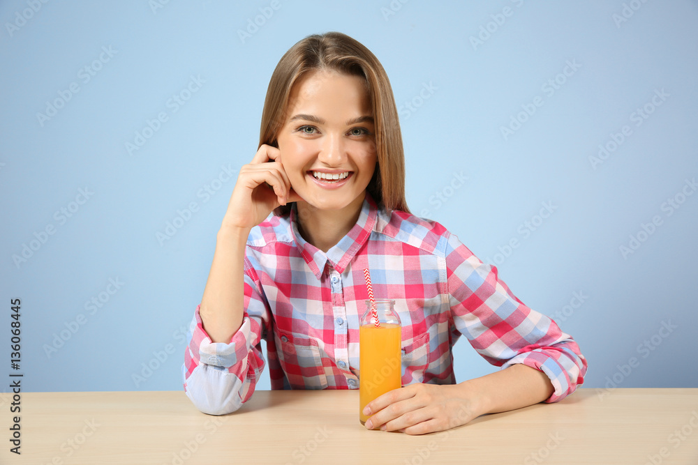 Young woman with glass of fresh juice sitting at the table Young woman with glass of fresh juice sitting at the table