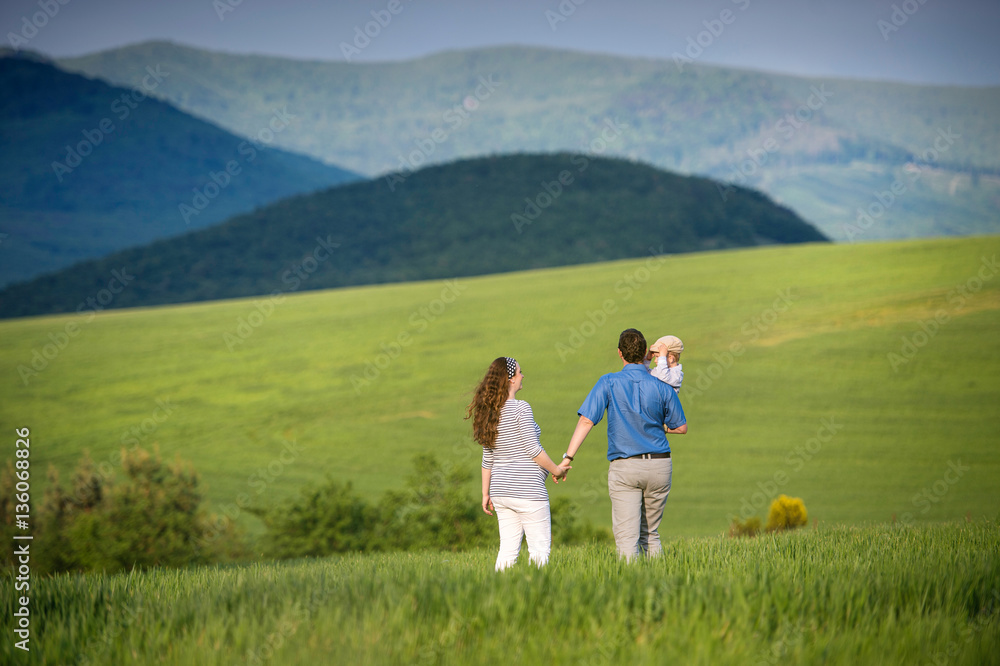 Young family on a walk against green fields and hills Young family on a walk against green fields and hills