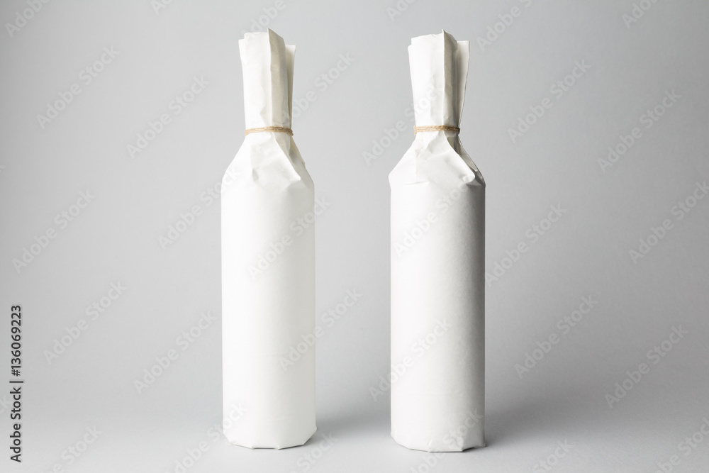 Two wine bottles are standing on gray background