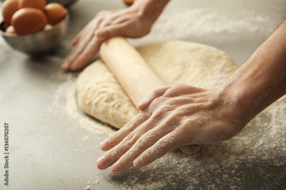 Man rolling out dough on kitchen table, close up Man rolling out dough on kitchen table, close up