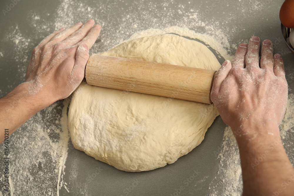 Man rolling out dough on kitchen table, close up Man rolling out dough on kitchen table, close up