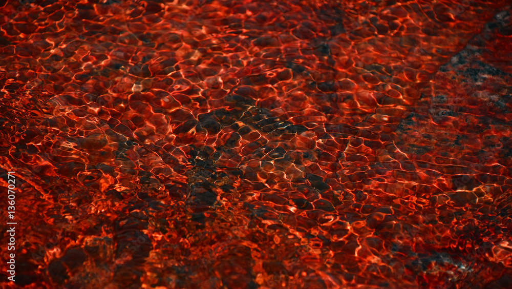 Red running water waves over stones Red running water waves over stones