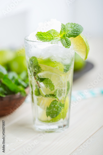 Fresh mojitos cocktail on wooden background. Mojitos with mint leaves, lime and ice. Drink making tools and ingredients for cocktail.