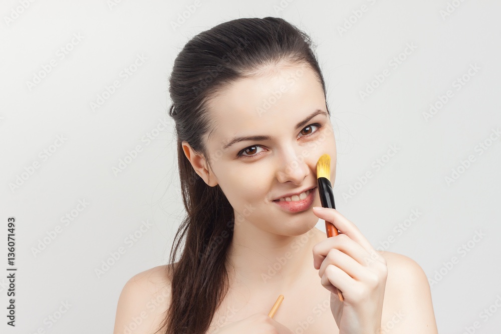 beautiful woman with makeup brush and bare shoulders beautiful woman with makeup brush and bare shoulders