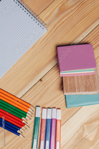 multicolored notebook on a wooden background and pencils