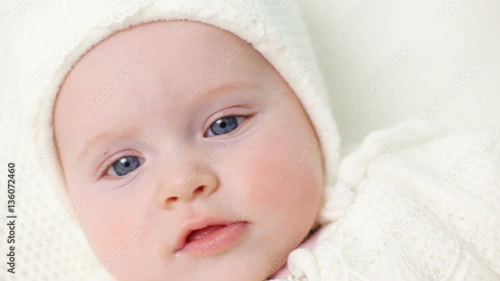 baby girl knitted in white overalls lying on the bed baby girl knitted in white overalls lying on the bed