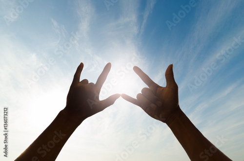 two silhouette human hand in beautiful shape of love against the sky and sun.