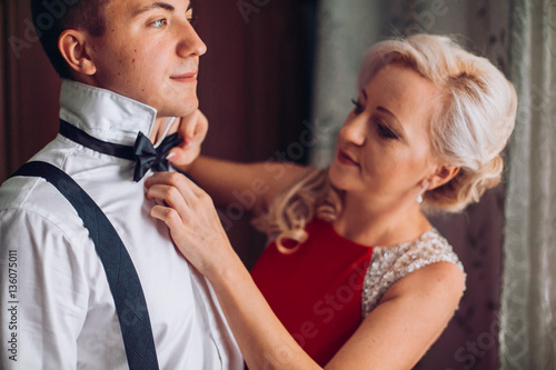 Obraz na płótnie Mother is helping with a bow-tie to her son before wedding ceremony. Concept mother and son. w salonie