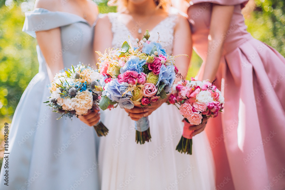 Amazing blond girls. Bride with bridesmaids with flowers hand in medow sunny pine forest.