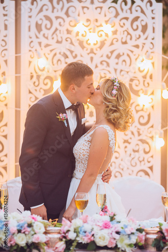 Emotional beautiful newlywed couple smiling and kissing at wedding reception