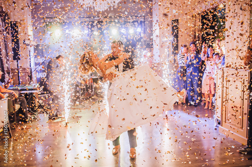 Obraz na płótnie Bride and groom first dance at wedding reception with firewoks and confetti. Kissing and swing couple in love. w salonie