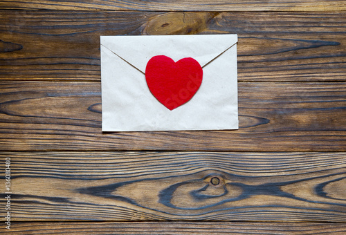 Love letter. Beautiful brown letter with red heart on wooden bac