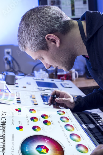 Young man in the process of offset printing and color correction
